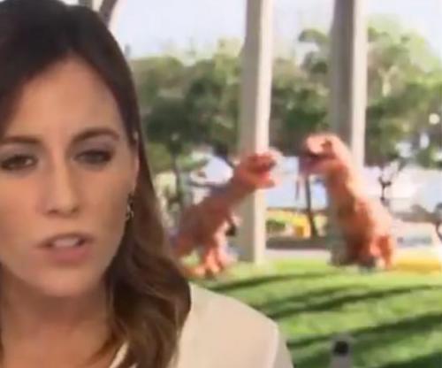 Frolicking-T-rexes-appear-in-background-of-live-news-segment