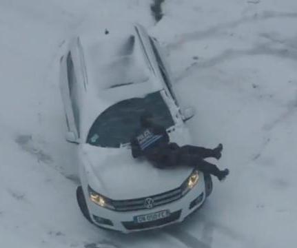 Police-officer-jumps-onto-runaway-car-on-snowy-hill